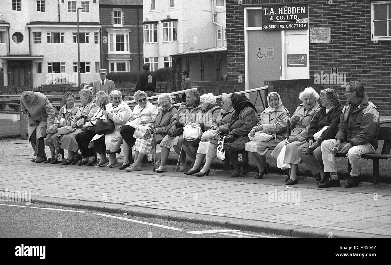 large-number-of-old-people-who-are-mostly-women-sitting-on-a-long-AR50AY.jpg